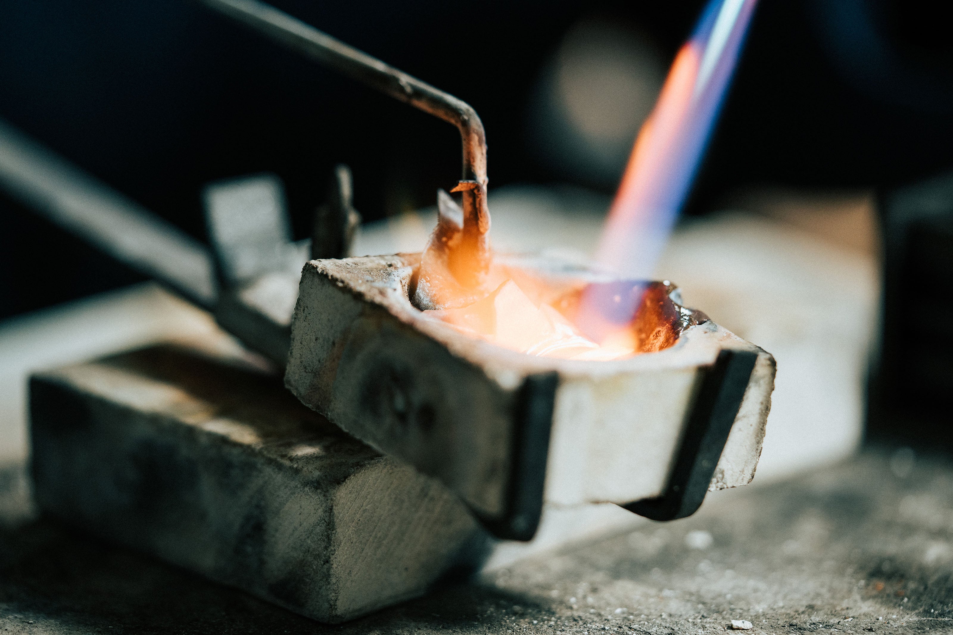 Molten metal being heated with a jeweller’s torch during the jewellery-making process, at our Jewellery Workshop in Plymouth.